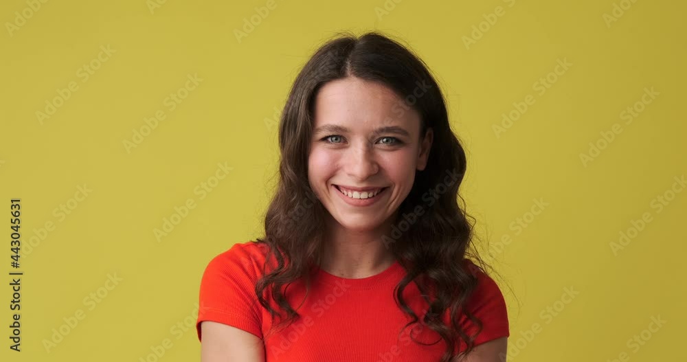 Woman winking her eye and showing ok gesture with hand over yellow background Woman winking her eye and showing ok gesture with hand over yellow background