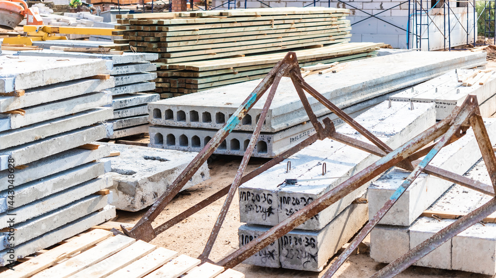 Reinforced concrete slabs and building materials at the construction site. Storage of materials for building a house. Industrial engineering. Reinforced concrete slabs and building materials at the construction site. Storage of materials for building a house. Industrial engineering.