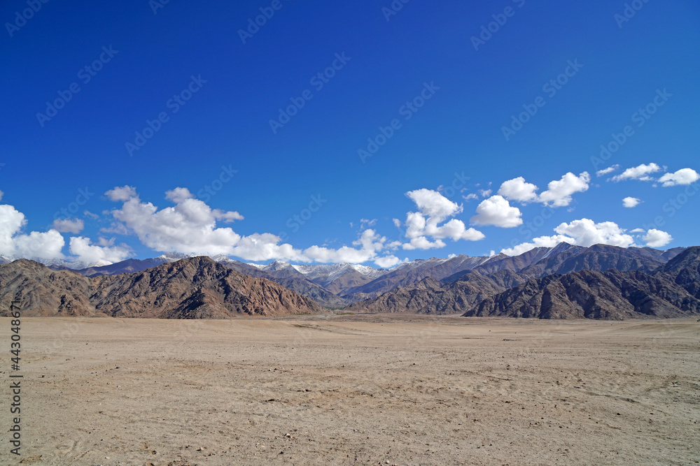 Landscape Nature scene of Desert Sand Land with himalaya snow mountain texture background  at Leh Ladakh , Jammu and Kashmir , India - blue and brown abstract outdoor travel