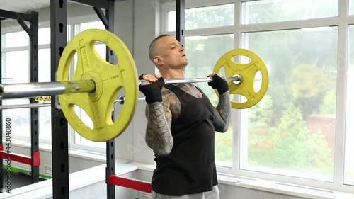 Man with tattoos doing barbell bench press