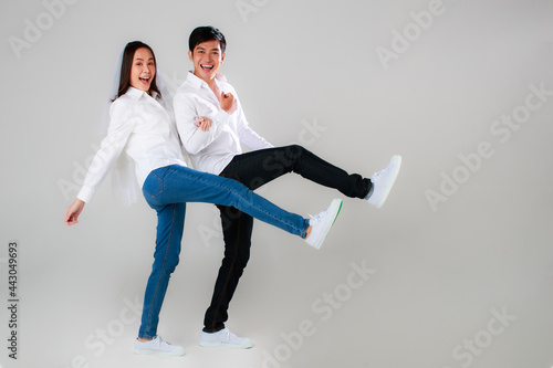 Young attractive Asian couple wearing white shirt and veil holding hands smiling against white background. Concept for pre wedding photography. Isolate