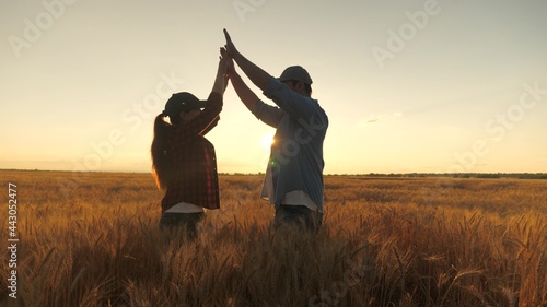 Happy business people, farmer, man and woman, greet each other with their hands in a wheat field. Agreed. Farmers and agronomist are talking, enjoying a good grain harvest in wheat field in sun.