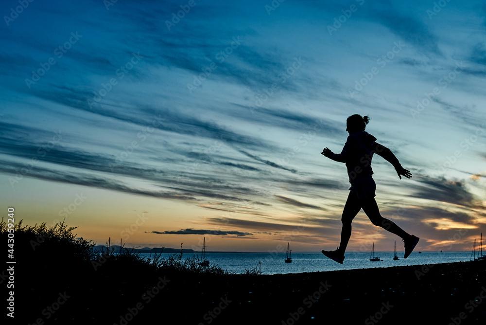 Fitness t woman running on the beach during summer vacation - Focus on silhouette