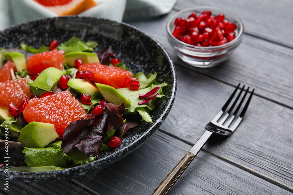 Plate with tasty grapefruit salad on dark wooden background Plate with tasty grapefruit salad on dark wooden background