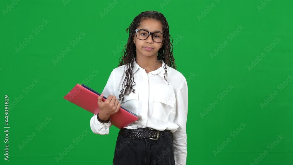 Portrait of nerd African American teen girl in eyeglasses looking through notes in workbook sighing looking at camera with dissatisfied facial expression on green screen. Bored genius at chromakey Portrait of nerd African American teen girl in eyeglasses looking through notes in workbook sighing looking at camera with dissatisfied facial expression on green screen. Bored genius at chromakey