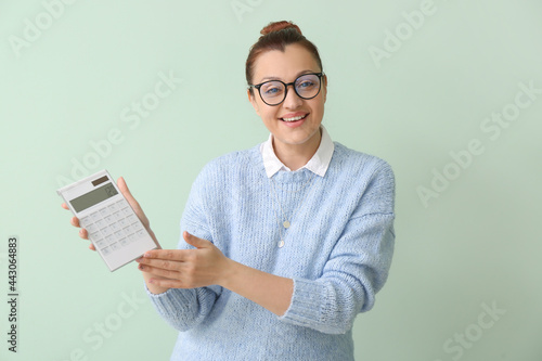 Portrait of female teacher with calculator on color background