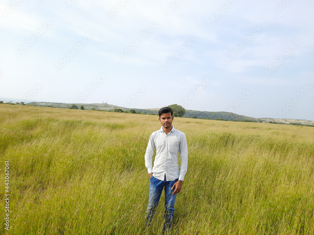 Indian young man, person on a meadow, young man in the wild, people in field. 