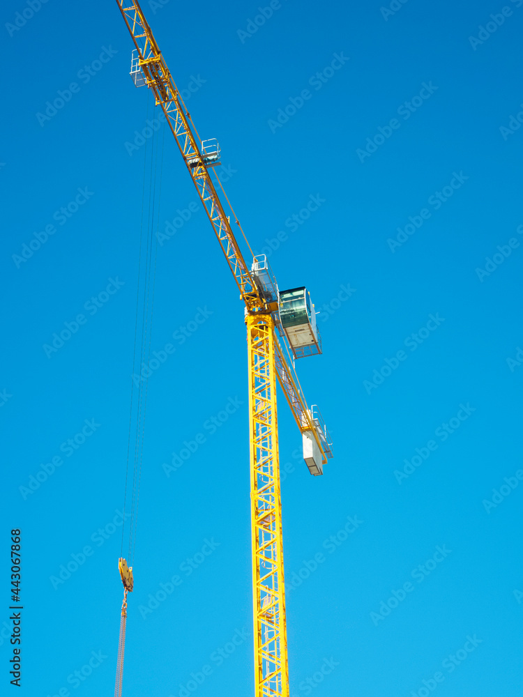 Isolated yellow construction crane in blue sky background. Isolated yellow construction crane in blue sky background.