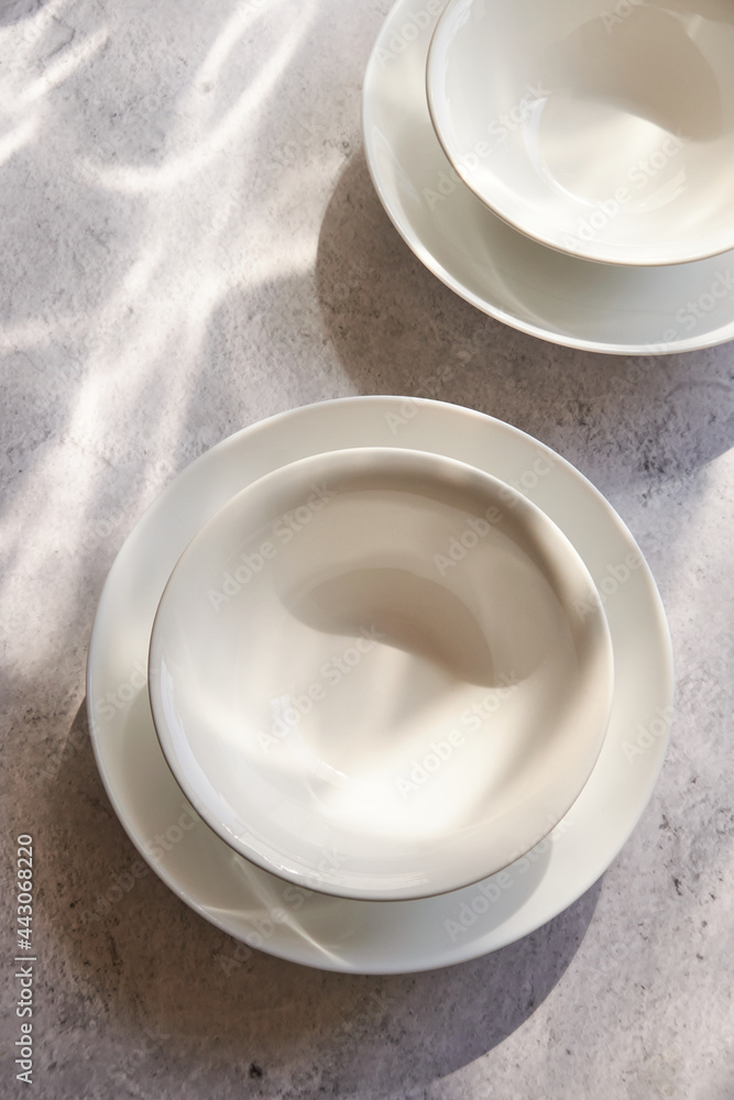 Empty white bowls on concrete, on a sunny table Empty white bowls on concrete, on a sunny table