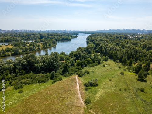 Green meadow near the river in summer. Aerial drone view.