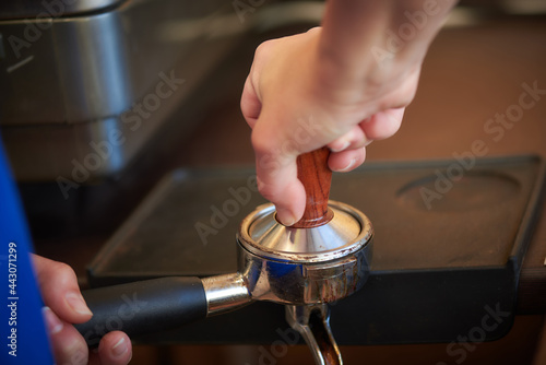 barista holds a press for freshly ground coffee beans for making coffee