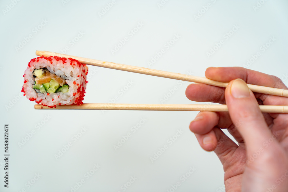 sushi sticks keep roll with caviar, fish, rice and avocado on white background sushi sticks keep roll with caviar, fish, rice and avocado on white background