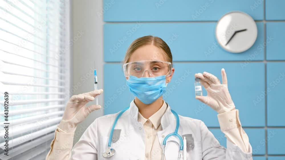 Young woman blonde in white coat holds syringe and vial Young woman blonde in white coat holds syringe and vial