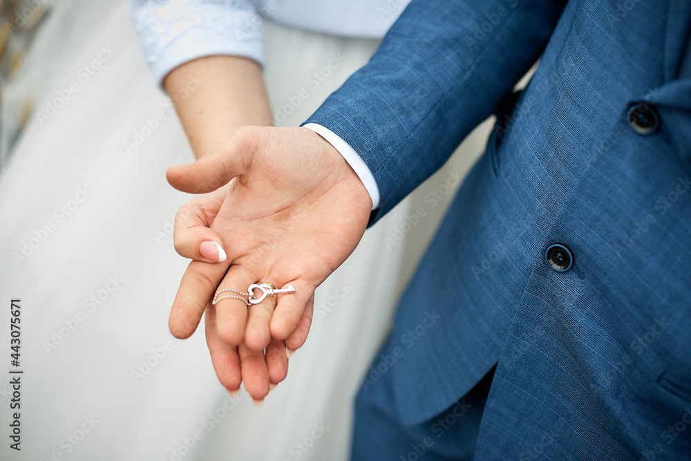 the hands of the bride and groom hold a small key.