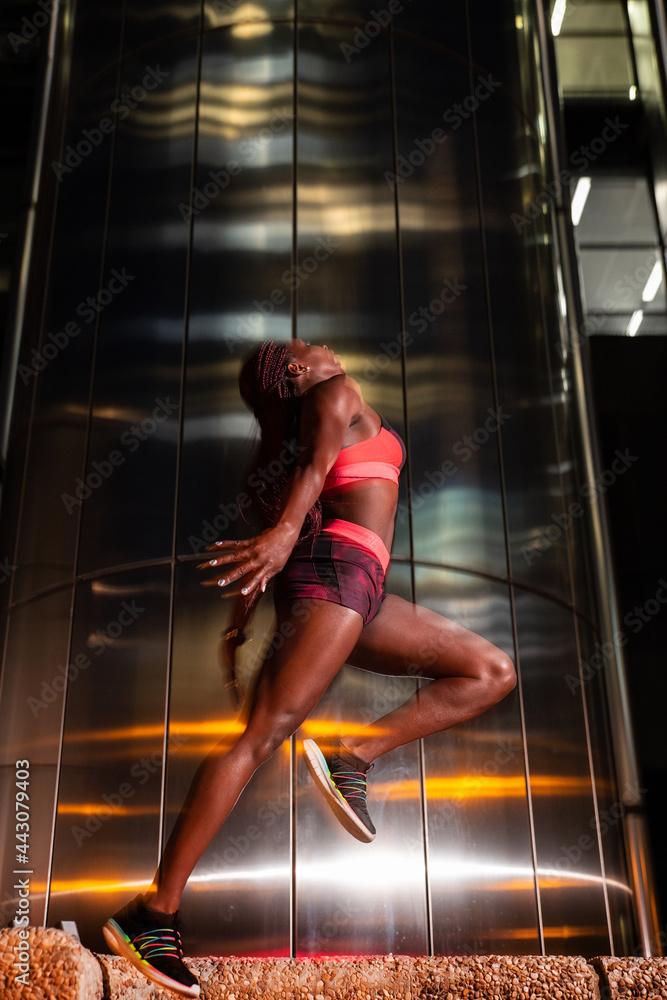 Ethnic sportswoman jumping on street at night Ethnic sportswoman jumping on street at night