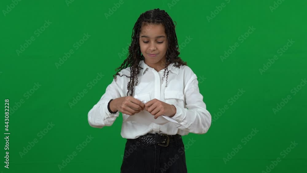 Stressed angry teen girl tearing paper on green screen crossing hands. Furious African American teenager ripping paper looking at camera with dissatisfied facial expression at chromakey background Stressed angry teen girl tearing paper on green screen crossing hands. Furious African American teenager ripping paper looking at camera with dissatisfied facial expression at chromakey background