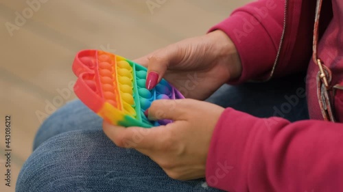 Wallpaper Mural Close-up of Young Woman Playing with Colorful Heart-Shaped Antistress Fidget Toy, Stress Relief with Popular Silicone Sensory Pop it Toy Torontodigital.ca