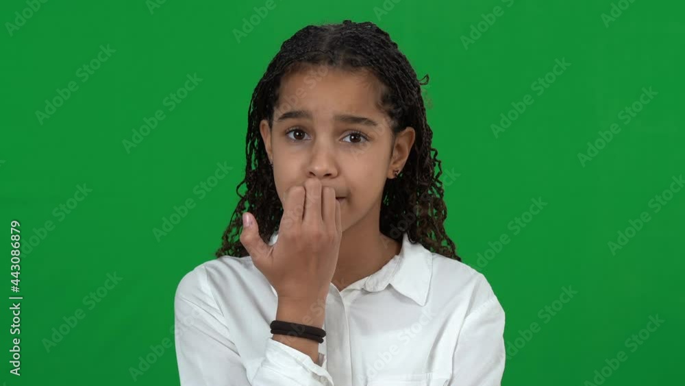 Nervous African American teen girl biting nails on green screen. Portrait of anxious worried teenager waiting for test results at chromakey background. Worries and nervousness concept Nervous African American teen girl biting nails on green screen. Portrait of anxious worried teenager waiting for test results at chromakey background. Worries and nervousness concept