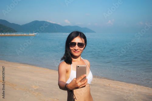 chinese woman on a beach in penang malaysia taking a selfie