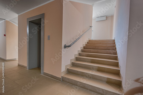 Building panel house interior with elevator and flight stairs. Precast concrete staircase. Flight of stairs. Flight of stairs are decorated building. Beautiful long staircase. Tile on floor. © spocktv