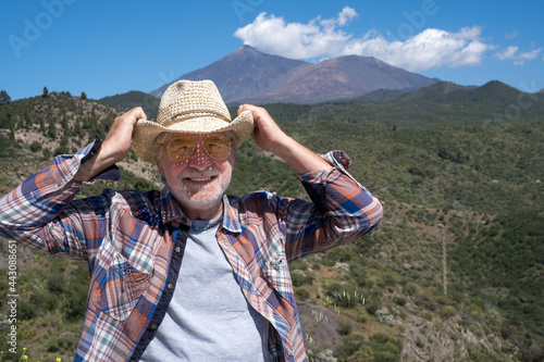 Attractive senior man with white beard enjoying outdoor excursion in mountain landscape, smiling looking at camera. El Teide volcan on background. © luciano