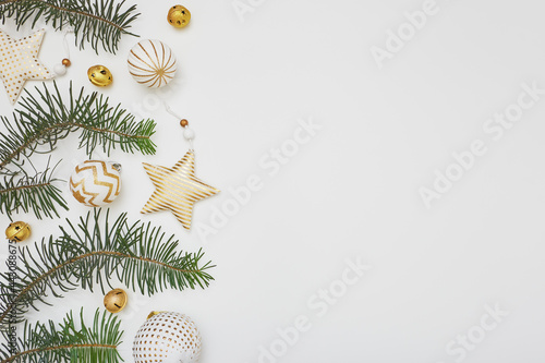 Christmas border made of fir tree branches and golden decorations on white background