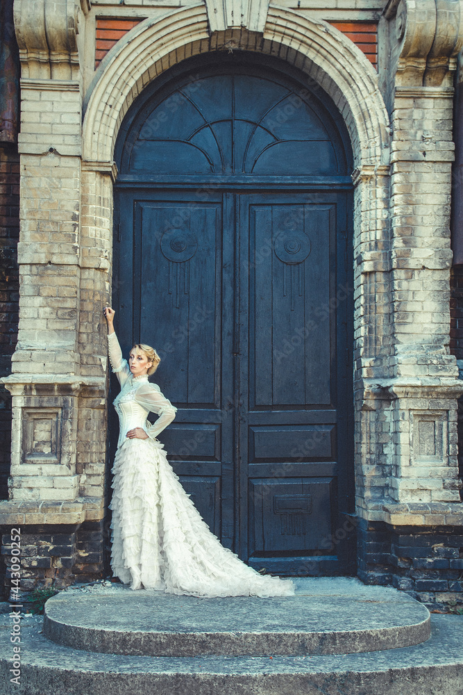 Blonde girl in a retro dress on the background of the old dark door