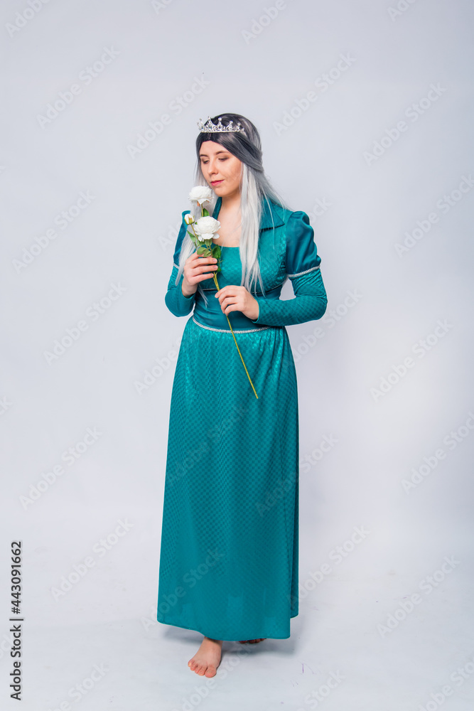 Full length portrait of a princess in a medieval, fantasy, turquoise dress with ash hair and a silver crown, posing with white roses in hands, isolated on a white background. Full length portrait of a princess in a medieval, fantasy, turquoise dress with ash hair and a silver crown, posing with white roses in hands, isolated on a white background.
