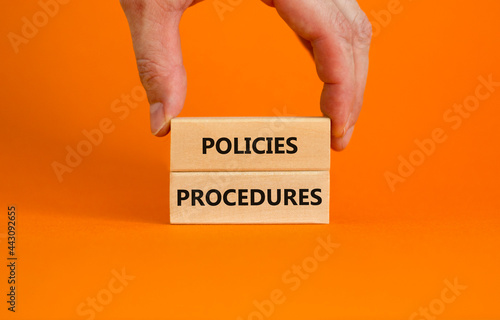 Policies and procedures symbol. Wooden blocks with concept words Policies procedures on orange background. Businessman hand. Business and policies and procedures concept. Copy space.