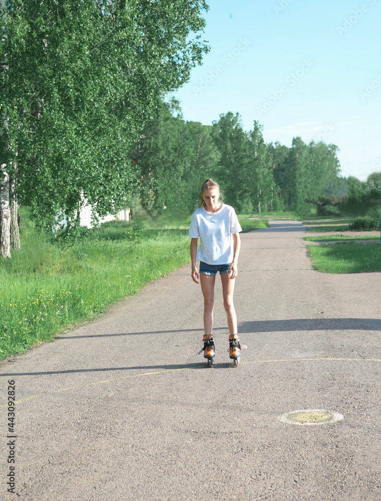 teenager girl roller skating in summer park. slim sporty girl wearing casual clothes. active leisure for tens