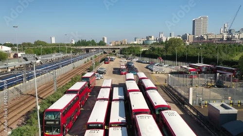 rows of red buses and double-deckers parking in company depot by railway track. Public transportation. London, UK