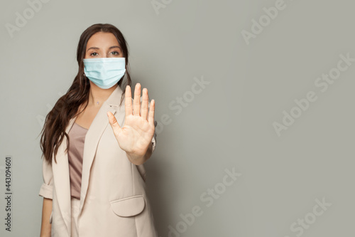 Stop COVID-19 gesture. Woman hand showing stop on gray background © artmim