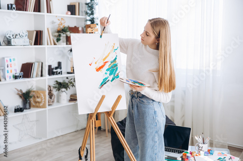 Young female artist painting picture in studio
