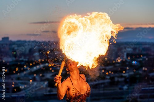 Fire-eater artist performing spit fire at sunset