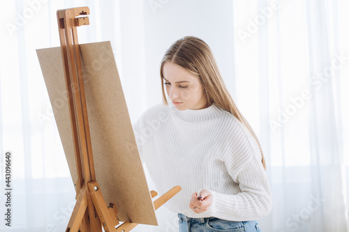 Young female artist painting picture in studio 
