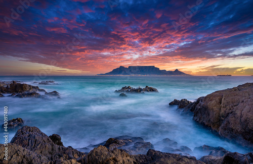 Beautiful sunset sky above a wispy long-exposure sea. Table Mountain sets the backdrop for a vibrant and colourful panorama
