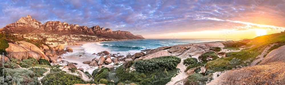 Naklejka premium Breathtaking sunset panorama of the iconic Table Mountain and the Twelve Apostles range, Cape Town South Africa. A unique and scenic wide-angle perspective taken from Maidens cove