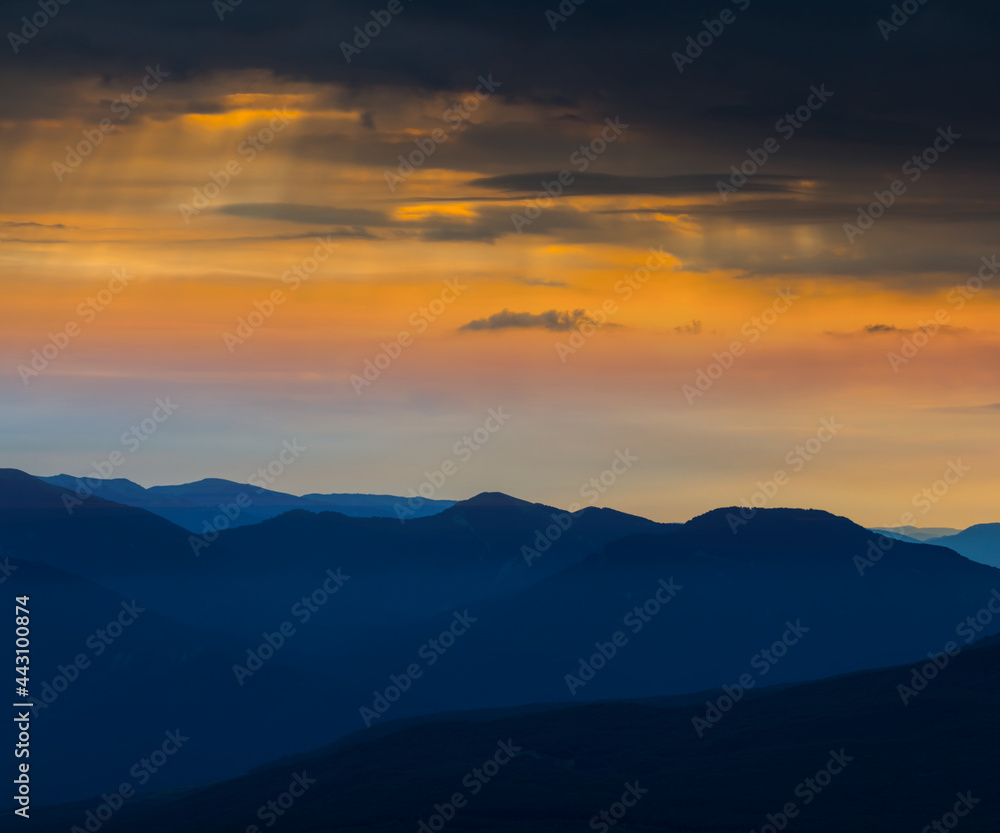 mountain chain silhouette under dramatic cloudy sky at the twilight