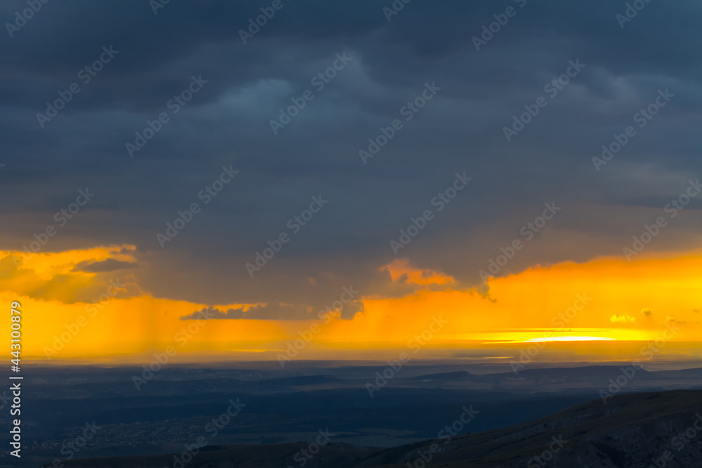 mountain chain silhouette under dramatic cloudy sky at the twilight