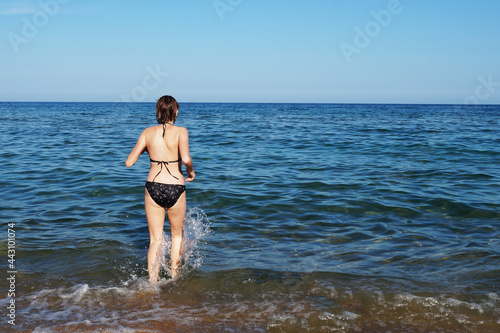 teenage girl running into the sea back view