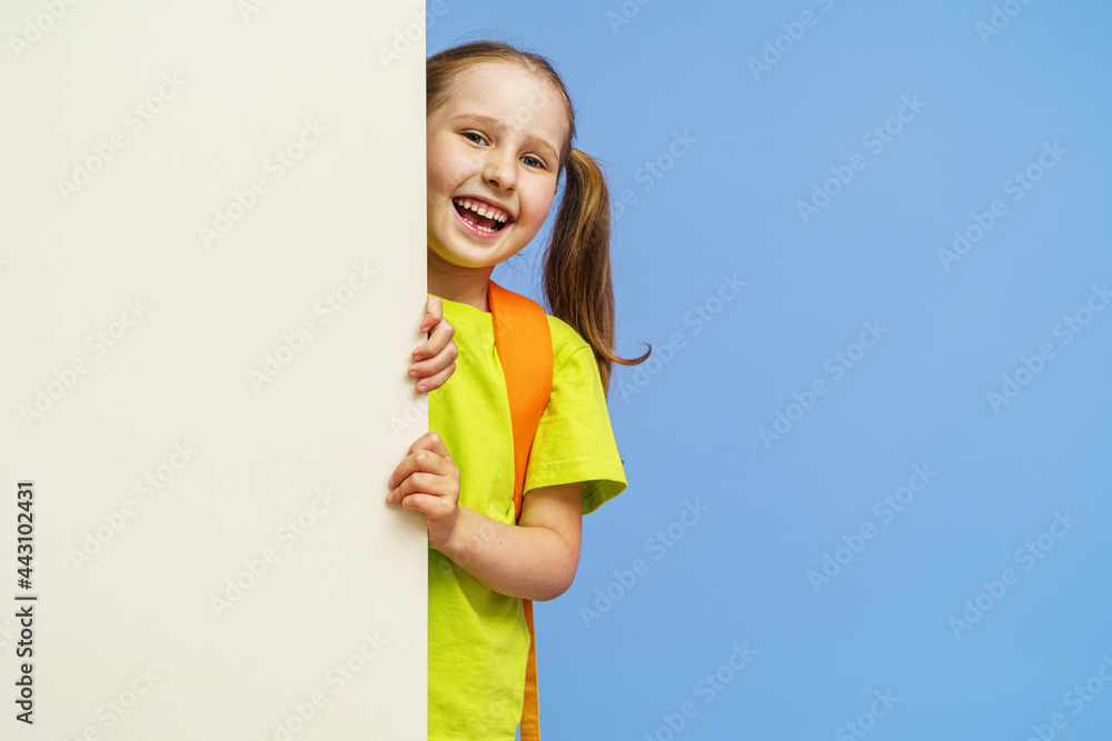happy little preschool girl, without one baby tooth, with two ponytails, looks out from behind the wall copying place for text. joyful, enthusiastic child in bright clothes flaunts. Advertising happy little preschool girl, without one baby tooth, with two ponytails, looks out from behind the wall copying place for text. joyful, enthusiastic child in bright clothes flaunts. Advertising