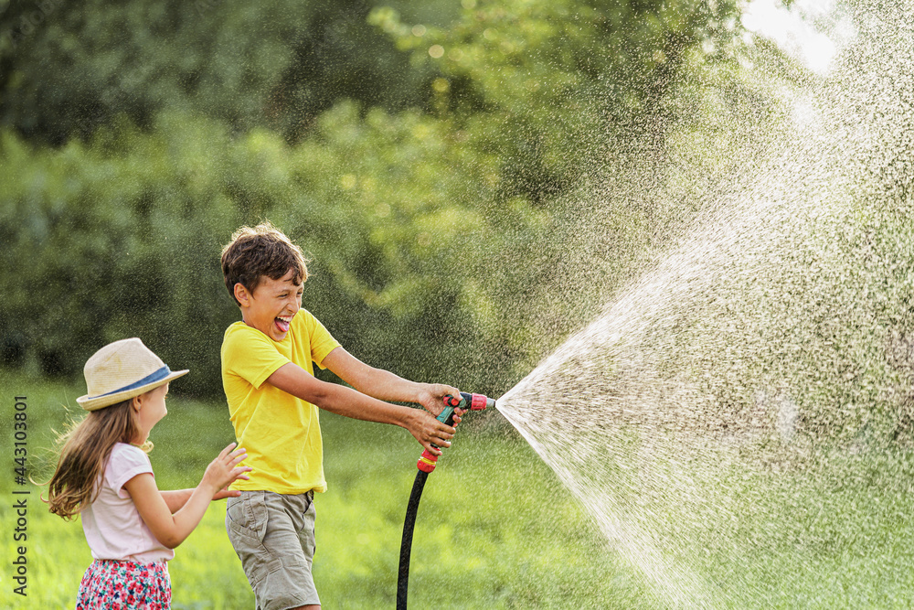 happy kigs splashes and plays with garden hose with sprinkler at sunset in  backyard, enjoys splashing water in heat. Summer entertainment and outdoor  recreation for children. Stock-Foto | Adobe Stock