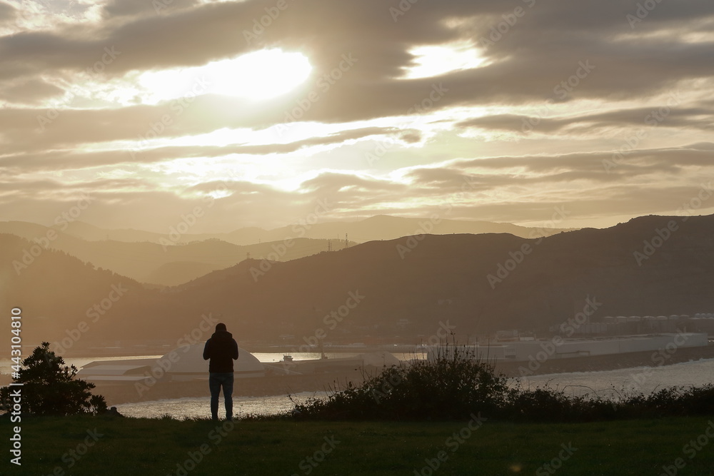 Contemplando la puesta de sol desde el acantilado de Punta Gálea, Getxo, Bizkaia, España. Vista al puerto de Bilbao.