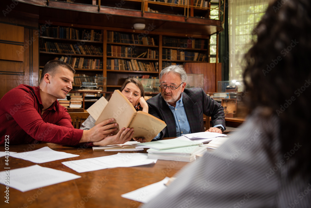 Group of students with professor. One of them holding a book Group of students with professor. One of them holding a book