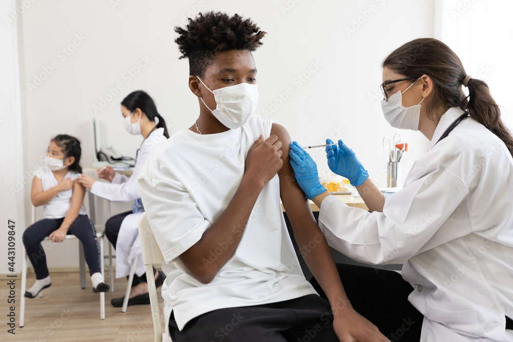 young male african wearing medical face mask and getting vaccinated from doctor, to build up or maintain immunity