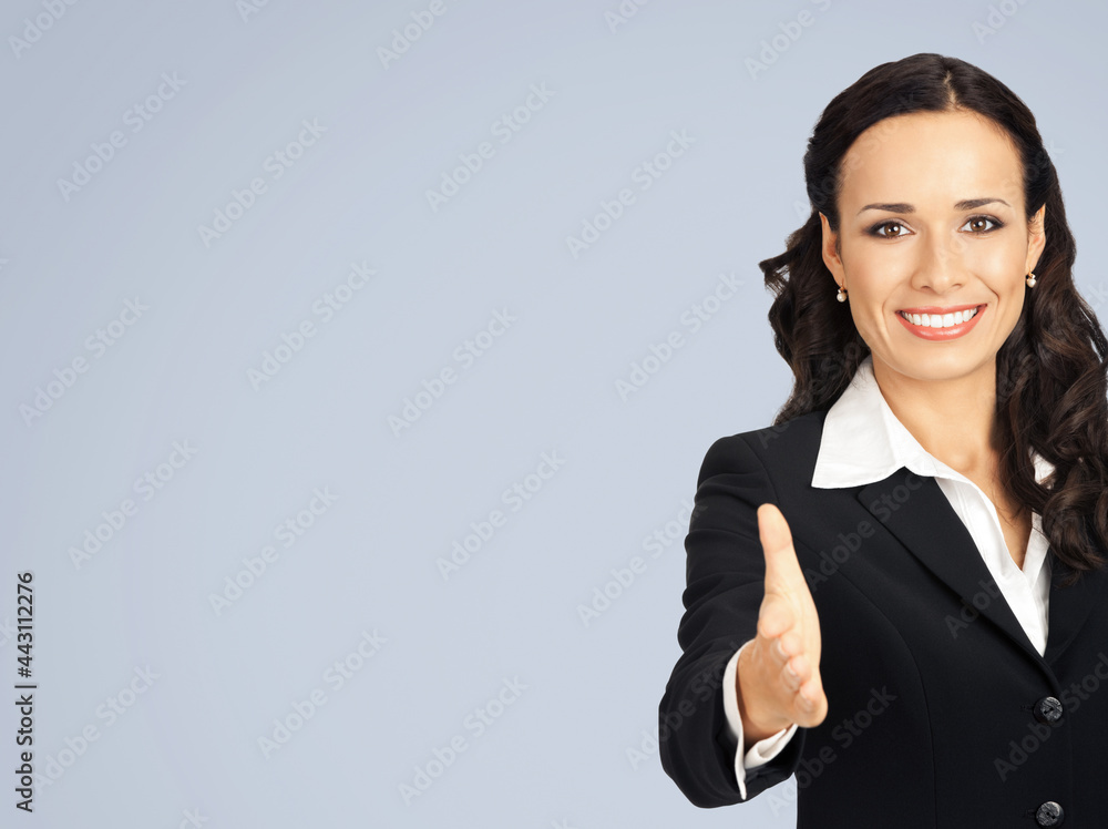 Image of smiling beautiful business woman in black confident suit and white blouse, giving hand for handshake, isolated over grey color background with copy space. Image of smiling beautiful business woman in black confident suit and white blouse, giving hand for handshake, isolated over grey color background with copy space.