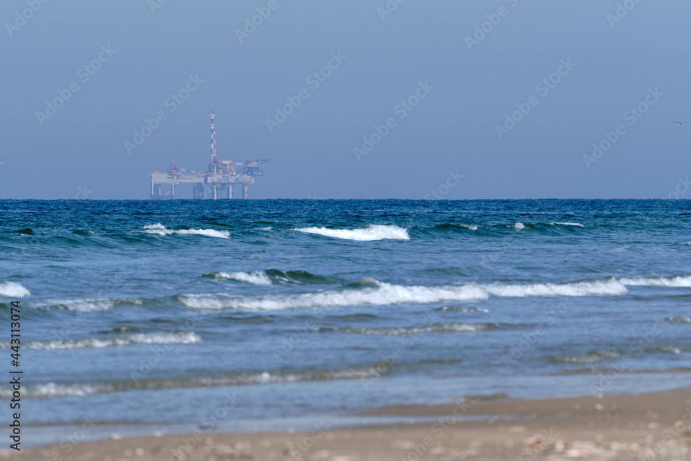 Ameland,Netherlands April 20,2021-NAM, Oil rig, offshore platform with beach, sand and surf. Natural gas extraction in the Wadden-North Sea Region, Wadden Island, nature conservation area:Het Oerd. Ameland,Netherlands April 20,2021-NAM, Oil rig, offshore platform with beach, sand and surf. Natural gas extraction in the Wadden-North Sea Region, Wadden Island, nature conservation area:Het Oerd.