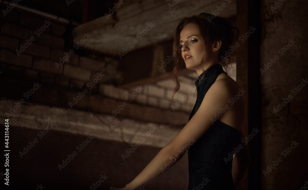Young beautiful woman in dress in a dark lane