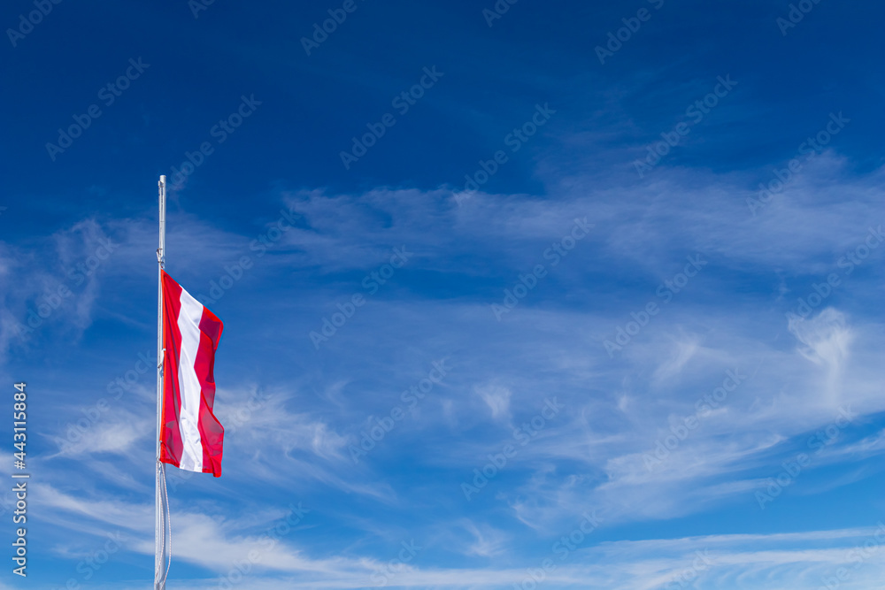 National flag of Austria against the clear blue sky, blown by the wind