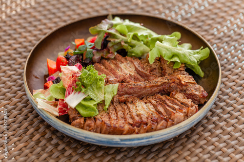 Fresh Beef Steak with Salad and Vegetables on Plate on Beach Outdoor Restaurant. Fine Dining Cuisine - Grilled Chopped T-bone Steak Served on Beachfront Cafe